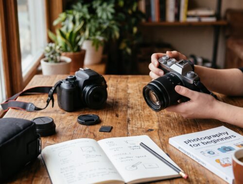 Ένα DSLR και μια mirrorless κάμερα πάνω σε ξύλινο τραπέζι, δίπλα σε σημειωματάριο με σημειώσεις για ISO και ταχύτητα κλείστρου